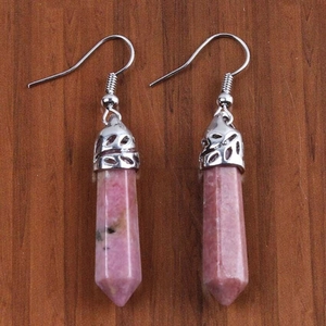 Dettaglio macro di orecchini di cristallo rosa esagonale con motivi a onde d'argento