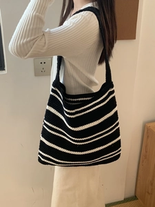 Detail of minimalist black and white striped knit shoulder bag on model's shoulder