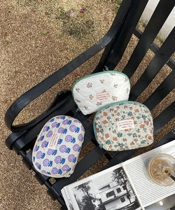 Quilted floral and cherry makeup bags displayed on a bench for travel storage