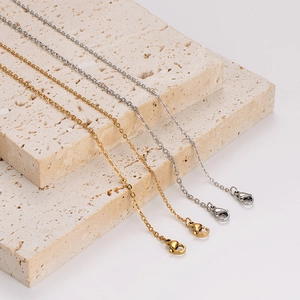 18K gold and silver stainless steel cable chains with lobster clasp on travertine stone