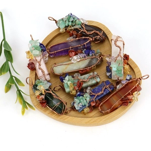 Handmade tree of life crystal pendants in heart-shaped wooden tray with natural stones