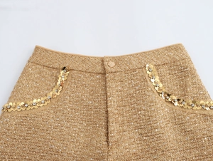 Detail of gold tweed shorts featuring intricate sequin and bead embellishments on the pocket