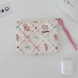 Detailed view of floral quilted pouch with pink wrist strap and cute poodle patterns