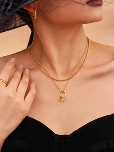 Close-up of a double-layer gold heart necklace and crystal earrings set on a model