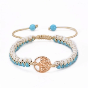 Detail of hand-woven turquoise and white stone bracelet with gold tree of life charm