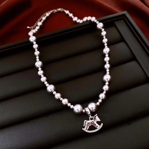 Close-up of a silver rocking horse pendant with gradient beads on a black jewelry tray
