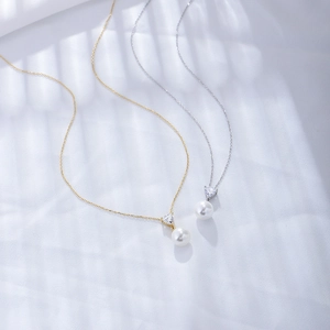 Detail view of heart-shaped zircon and white pearl pendants on gold and silver chains
