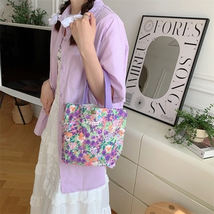 Dettaglio della borsa tote in tela floreale con manici viola e bottone a scatto in bronzo
