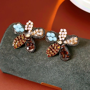 Macro view of floral stud earrings featuring colorful rhinestones on a dark base