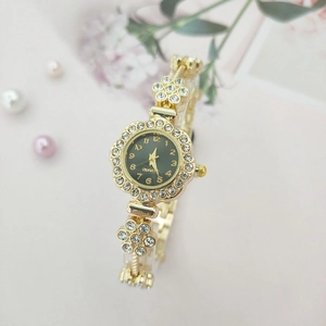 Detailed close-up of a floral golden watch with rhinestones and black quartz dial