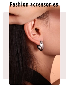 Close-up of chunky silver oval hoop earrings worn by a model with polished metal finish