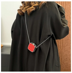 Close-up of red glitter acrylic mini bag with silver chain strap shown on a model back