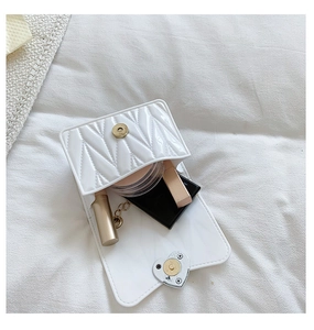 Detail view of white quilted mini bag showing interior space for small cosmetics