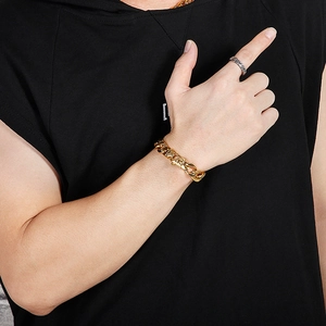 Close-up of a men's chunky gold Cuban link bracelet and silver ring on a model's hand