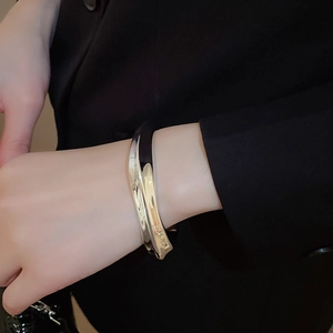 Bracelet large en métal argenté plissé porté au poignet sur un costume noir élégant