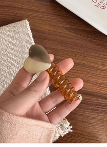 Detail of a spiral hair coil with heart ornament in amber and beige gradient finish