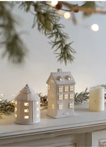 Detail of white ceramic house lamps with hollow windows and warm yellow LED light