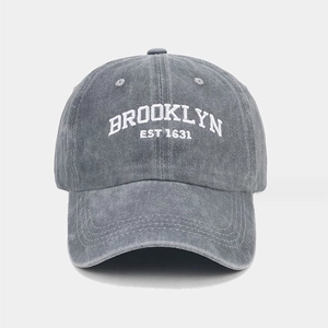 Close-up of white Brooklyn embroidery on washed grey cotton baseball cap with retro texture