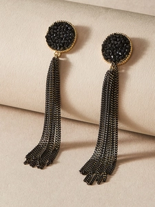 Macro shot of black faceted gemstone stud with long golden edge and dark chain tassels