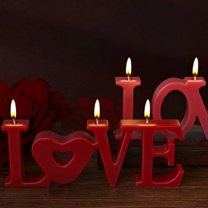 Romantic burning LOVE letter candles on wood display with floral background decor