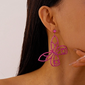 Close-up of pink butterfly drop earrings featuring sparkling rhinestones on a model