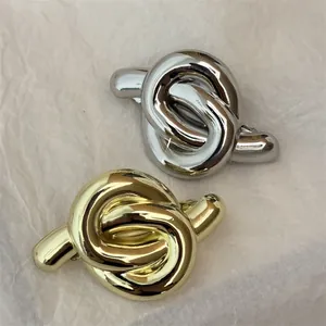 Close-up of gold and silver knot-style hair clips with a polished metallic mirror finish