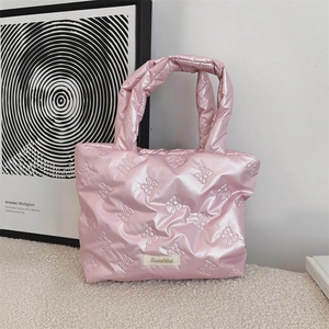 Dettaglio borsa trapuntata rosa con motivi a fiocco ed etichetta logo tessuta