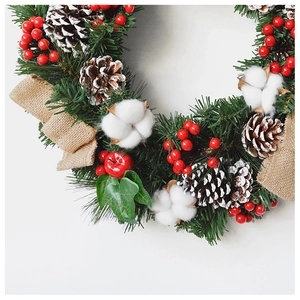 Close-up of Christmas wreath with pine cones, red berries, cotton flowers and burlap bow