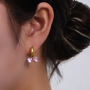 Close-up of gold hoop earring with pink heart-shaped zircons forming a butterfly
