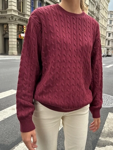 Close-up of wine red knit sweater featuring a classic thick cable stitch texture
