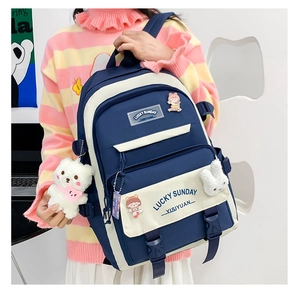 Detail of navy and beige school backpack with cute lucky sunday patches and bear pendant