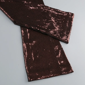 Close-up of dense deep red sequins on a backless halter jumpsuit evening dress