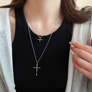 Close-up of double-layered silver cross necklace worn by a model on black background