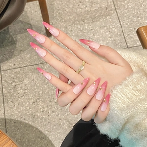 Pink ombre almond press-on nails with gold stars and pearl accents on hands