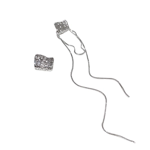 Boucles d'oreilles asymétriques argentées avec texture géométrique et longs pompons
