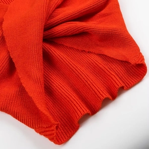 Dettaglio ravvicinato della trama in maglia arancione e cuciture del maglione alla moda