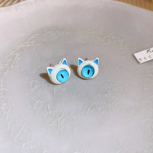 Detail of sweet cat-shaped stud earrings with blue feline eyes and white enamel finish
