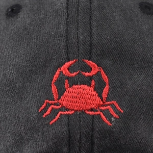Close-up of red crab embroidery on black washed vintage cotton baseball cap detail