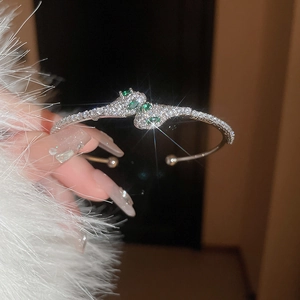 Close-up of silver snake cuff bracelet with emerald eyes and sparkling zircons