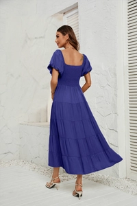 Détail de la robe bleue à manches bouffantes montrant le tissu texturé et le dos fluide