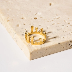 Minimalist gold-plated irregular fluid crown ring on a travertine stone display