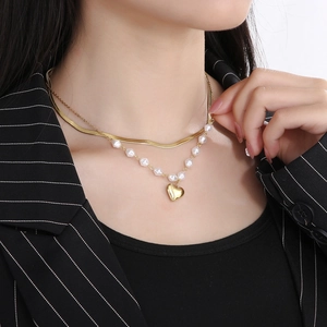 Close-up of double-layer titanium necklace with golden heart pendant and white pearls