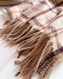 Detail of beige and brown checkered scarf featuring soft knit texture and woven tassels