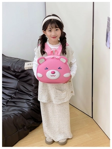 Pink cartoon bear hardshell backpack for kids with 3D ears shown by a child model