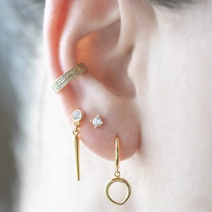 Close-up of gold-plated spiked earrings set with sparkling zircon in a stylish ear stack