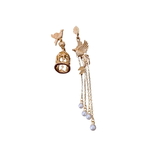 Asymmetric gold birdcage earrings with pearls and long tassels on a white background