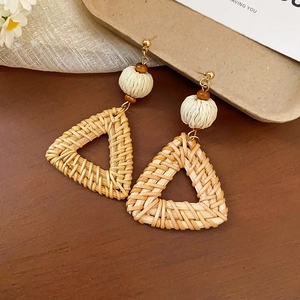 Detailed macro view of bohemian handmade triangle woven rattan earrings with gold stud