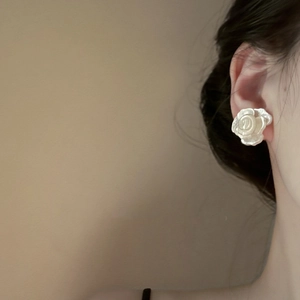 Detailed close-up of a silver-toned multi-layered flower earring on a model's ear