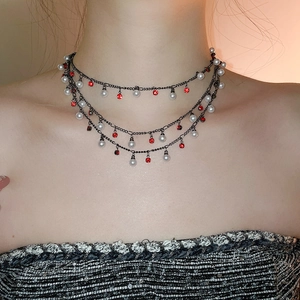 Detailed view of triple-layered choker with white pearls and red rhinestone charms