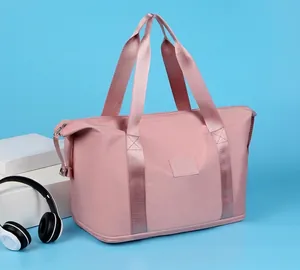 Pink nylon travel bag detail showing wide handles and bottom dry-wet separation layer